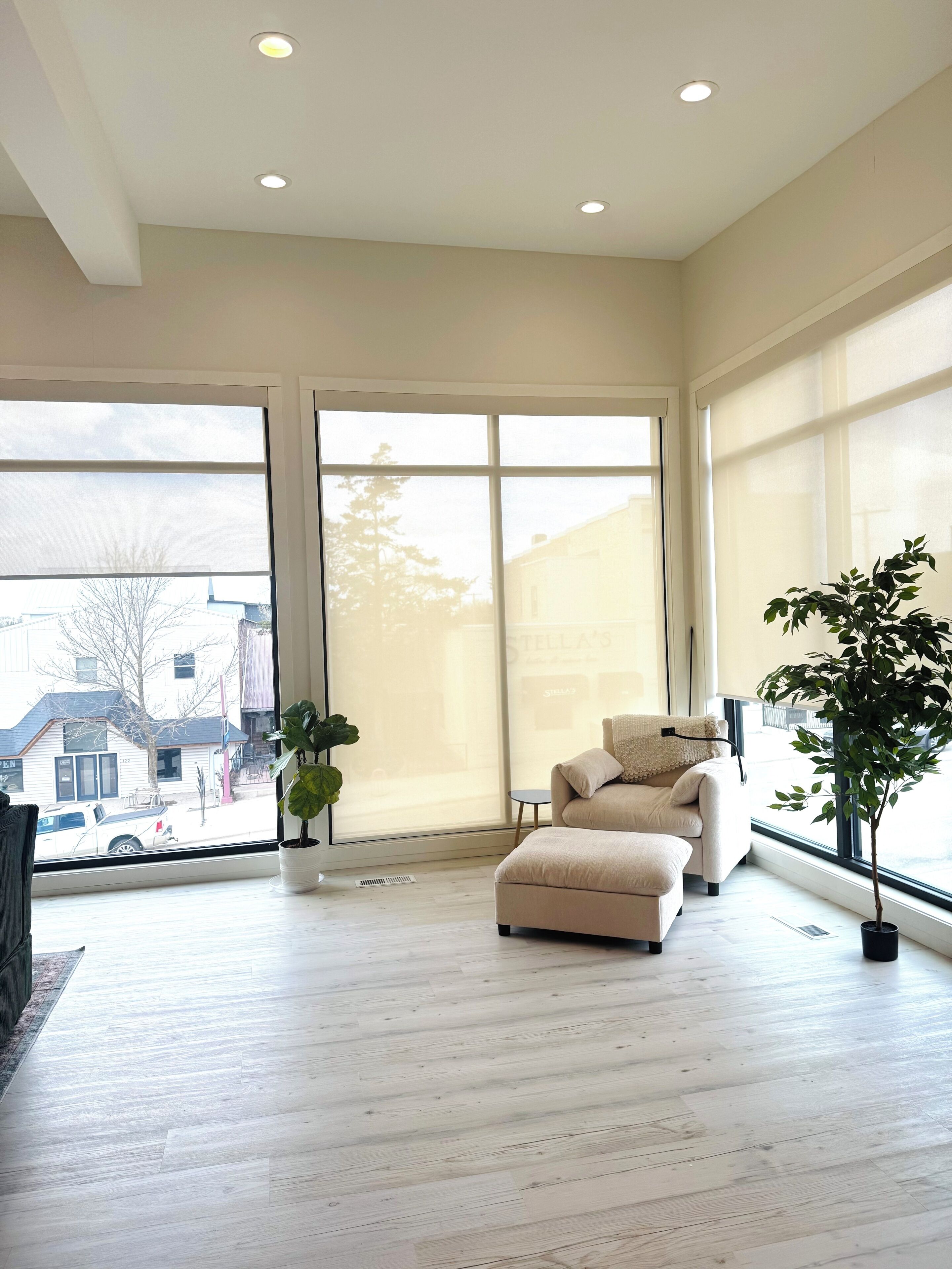 A spacious room with a large sliding glass door, a beige sofa, a small round table, and a potted plant.. NeverHome. Steps to town. Minutes from the lake.