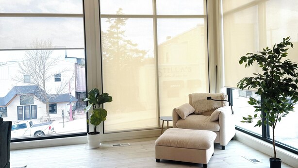 A spacious room with a large sliding glass door, a beige sofa, a small round table, and a potted plant.