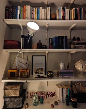 A bookshelf with books, decorative items, and a framed quote. - BB Suite Florence – Elegance, Comfort, Hospitality. (Firenze)