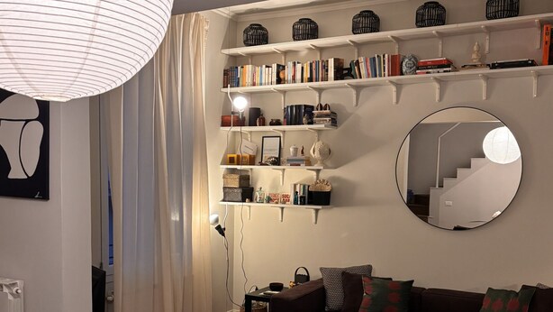 A modern living room with a wooden dining table, a sofa, and a round mirror on the wall. - BB Suite Florence – Elegance, Comfort, Hospitality. (Firenze)