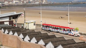 A beachside train station with a coastal view, a sandy beach, and a row of white houses in the background. - Memory Maker (Bridlington)