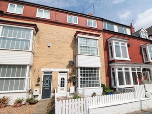 A two-story residential building with a brick facade, white window frames, and a white picket fence. - Memory Maker (Bridlington)