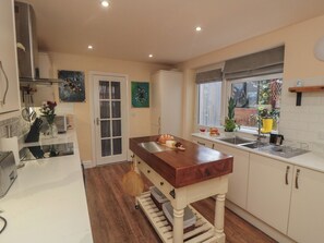A kitchen with a wooden island, white cabinets, a window with a view, and a door with glass panels. - Memory Maker (Bridlington)