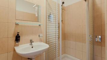 A bathroom with a sink, mirror, and shower enclosure.