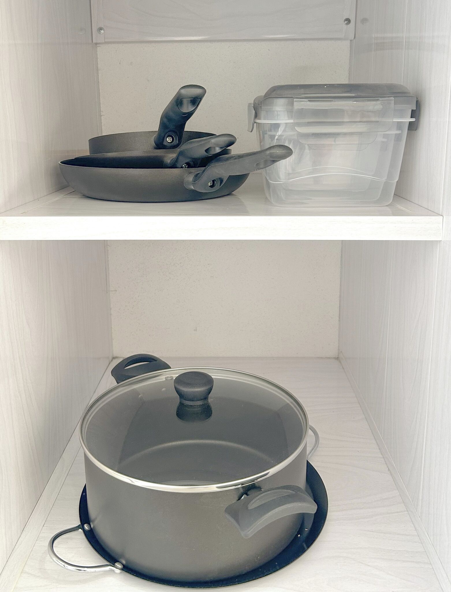 Una cocina con una olla en el estante inferior y una sartén en el superior.