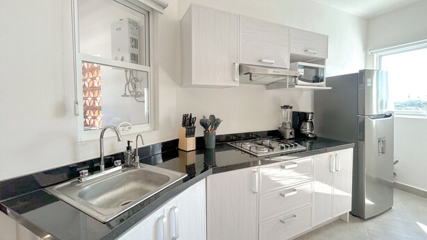 Een moderne keuken met een roestvrijstalen koelkast, een magnetron, een gasfornuis en een spoelbak.