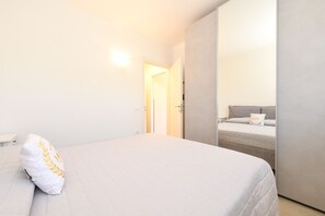 Ein Schlafzimmer mit einem Bett, einem Nachttisch, einem Kleiderschrank und einer Tür zu einem anderen Raum.
