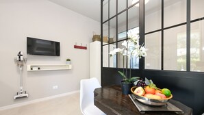 A modern dining area with a dark wooden table, white chair, and a fruit bowl. - MGH- AMAI Small Holiday Cottage (Manerba del Garda)