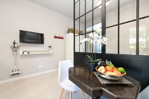A modern dining area with a dark wooden table, white chair, and a fruit bowl. - MGH- AMAI Small Holiday Cottage (Manerba del Garda)