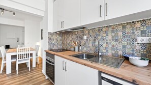 Une cuisine moderne avec des armoires blanches, un plan de travail en bois et un revêtement mural décoratif.