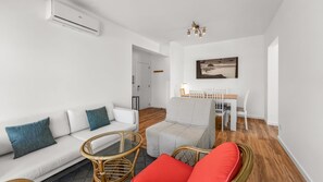 Un salon moderne avec un canapé blanc, une table à manger avec des chaises et une table basse en osier.