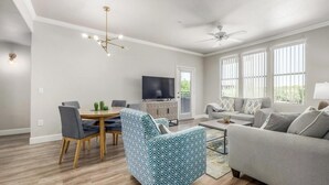 Ein modernes Wohnzimmer mit Essbereich, einem Fernseher und einem Deckenventilator.