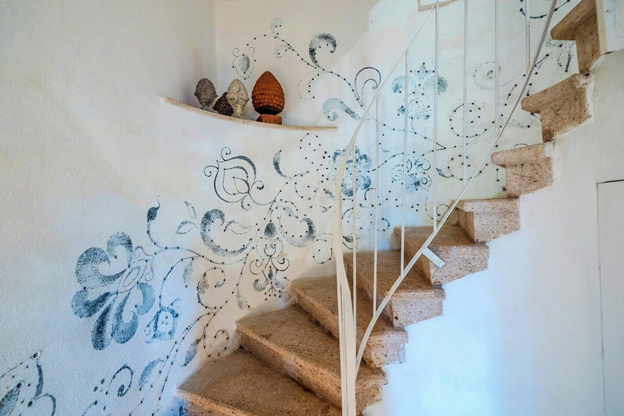 A staircase with a decorative wall mural and a shelf with decorative items.