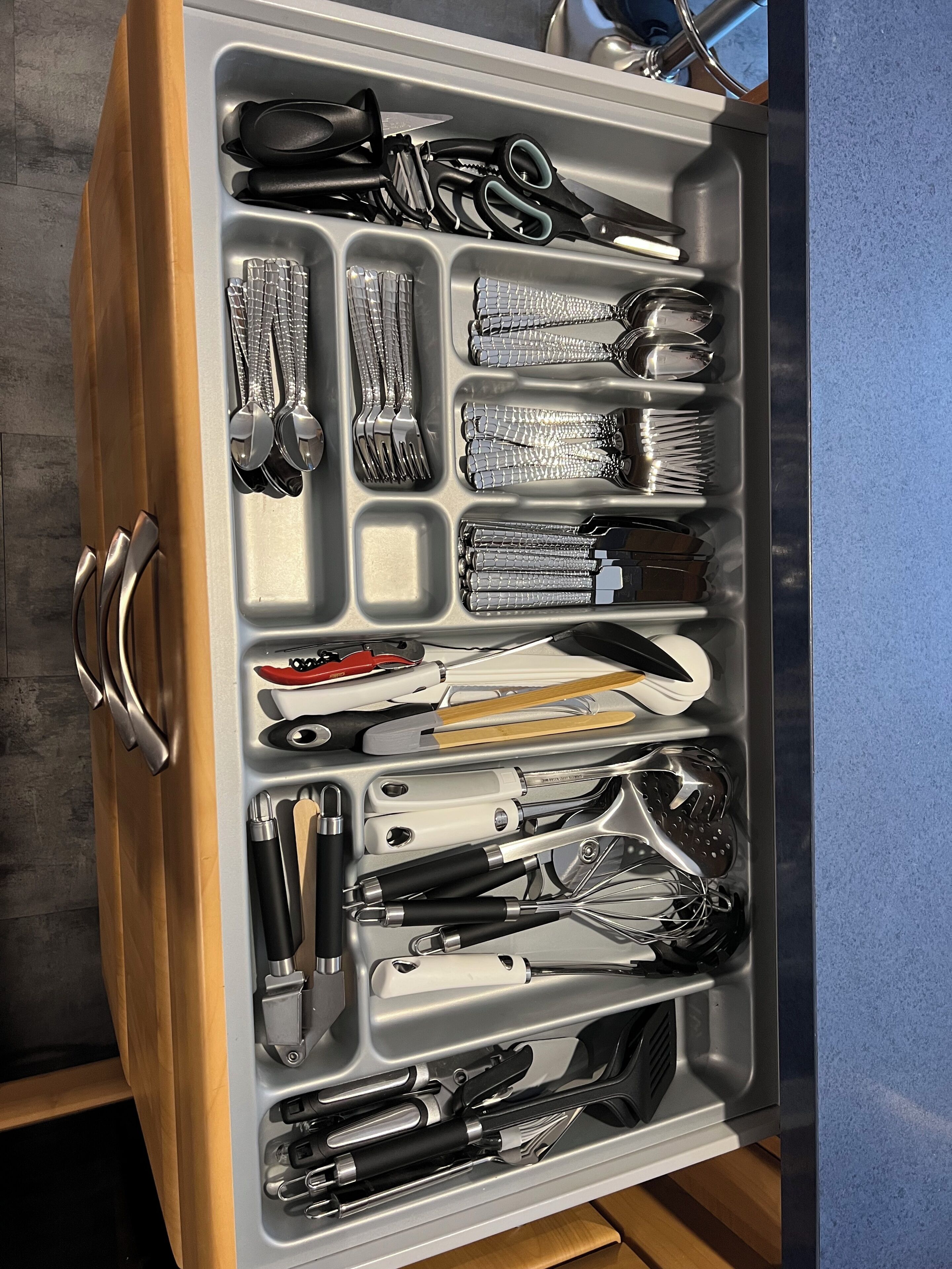 Un tiroir contenant divers ustensiles et outils de cuisine, notamment des couteaux, des ciseaux et un fouet.