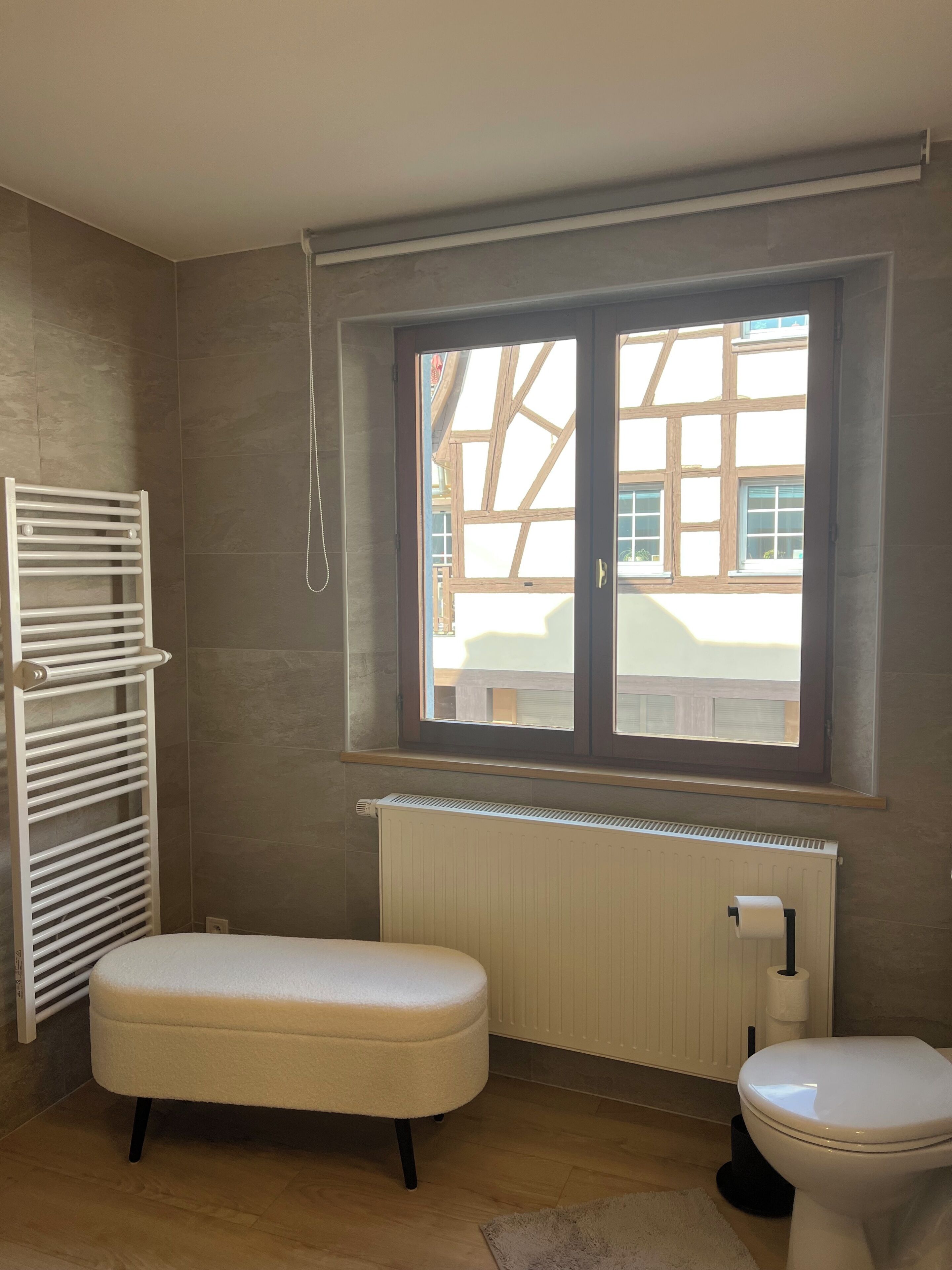 Un bagno con finestra, termosifone, WC e panchetta.