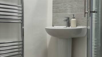 Un bagno moderno con box doccia in vetro, lavandino a colonna bianco e water.