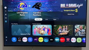 En tv-skärm som visar ett användargränssnitt för en sportkanal, med en fotbollsmatch mellan Los Angeles Rams och Carolina Panthers.