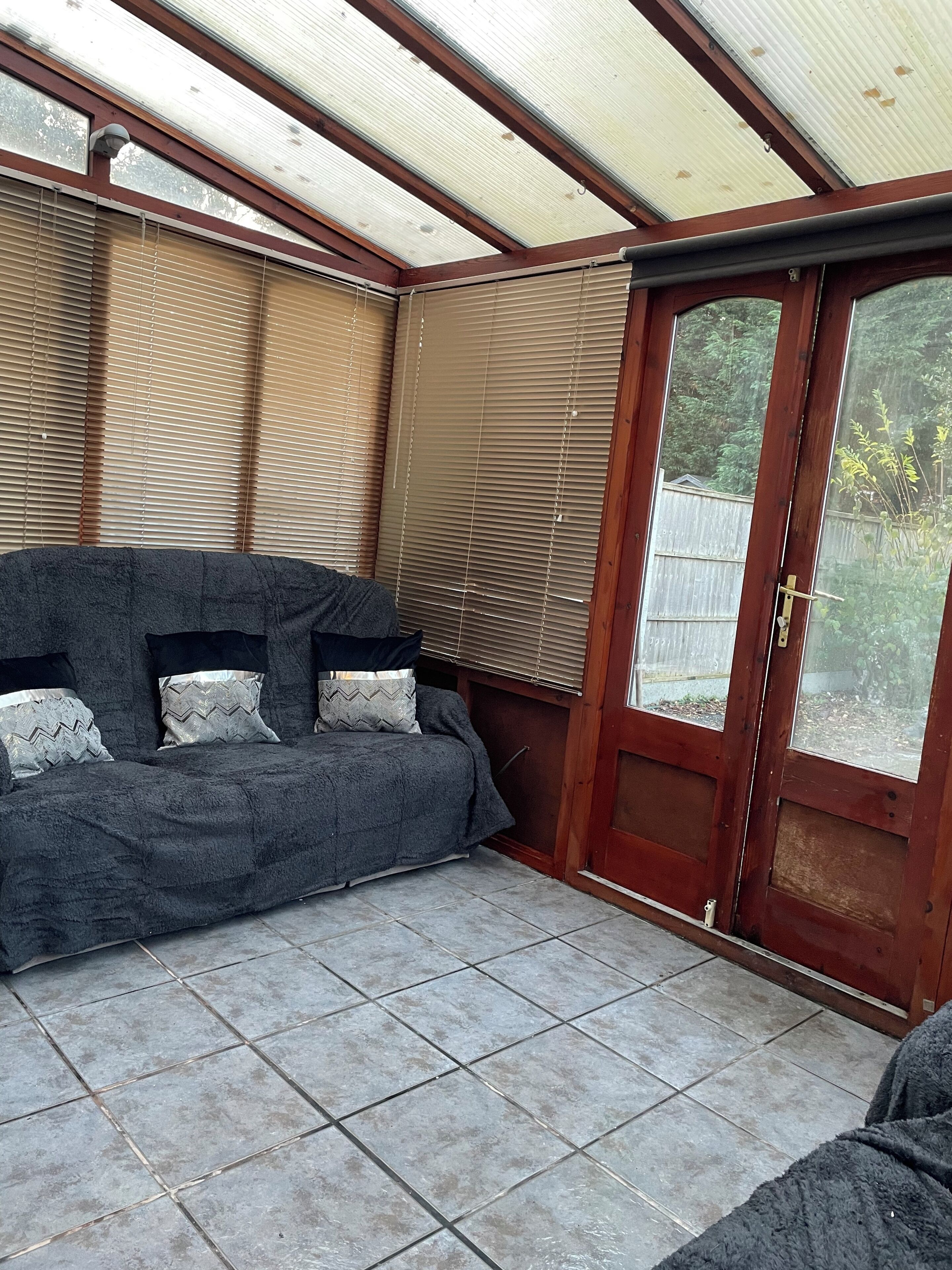 Ein Zimmer mit einer Couch, einer Schiebetür aus Glas und einem gefliesten Boden.