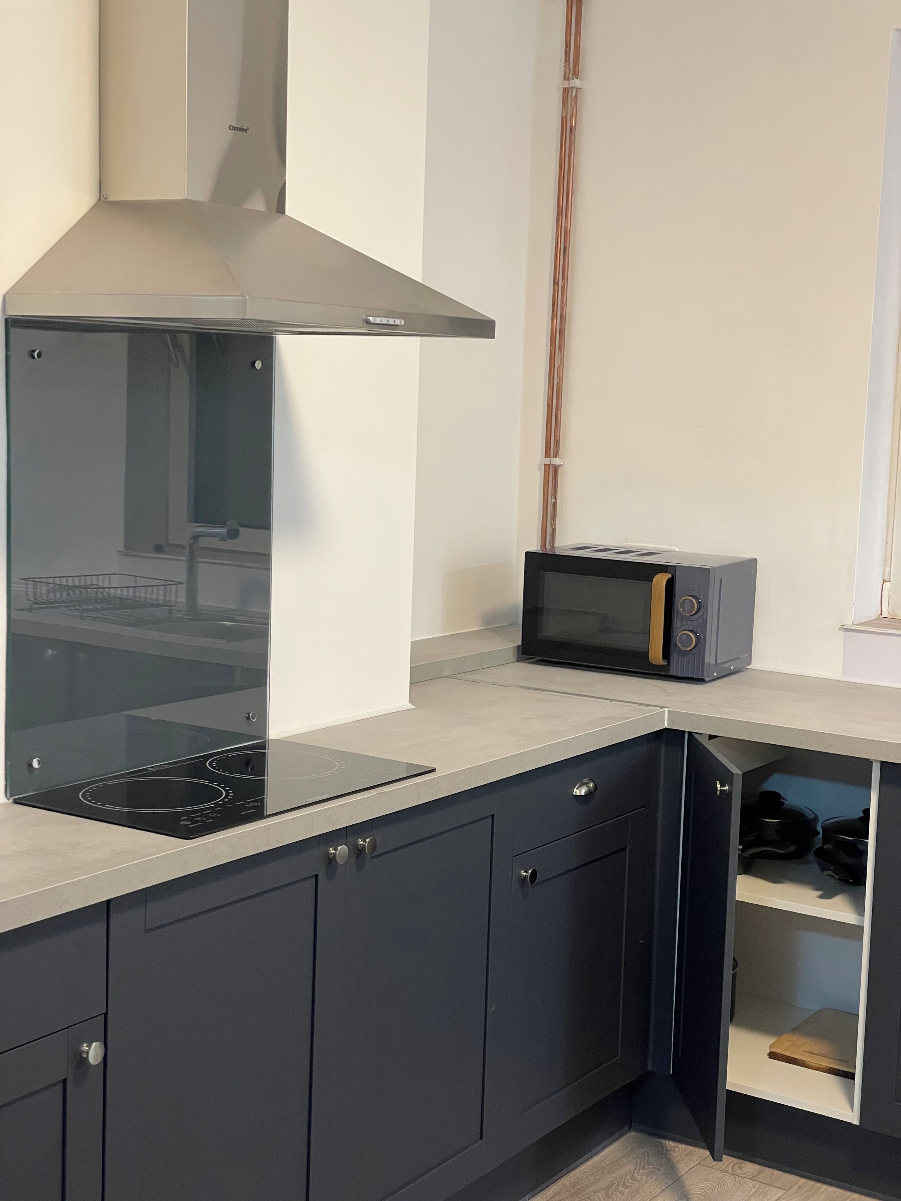 Una cocina con estufa, microondas y armarios.