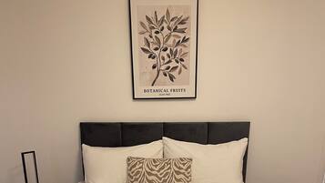 A neatly made bed with a textured blanket, two pillows, and a pair of towels.