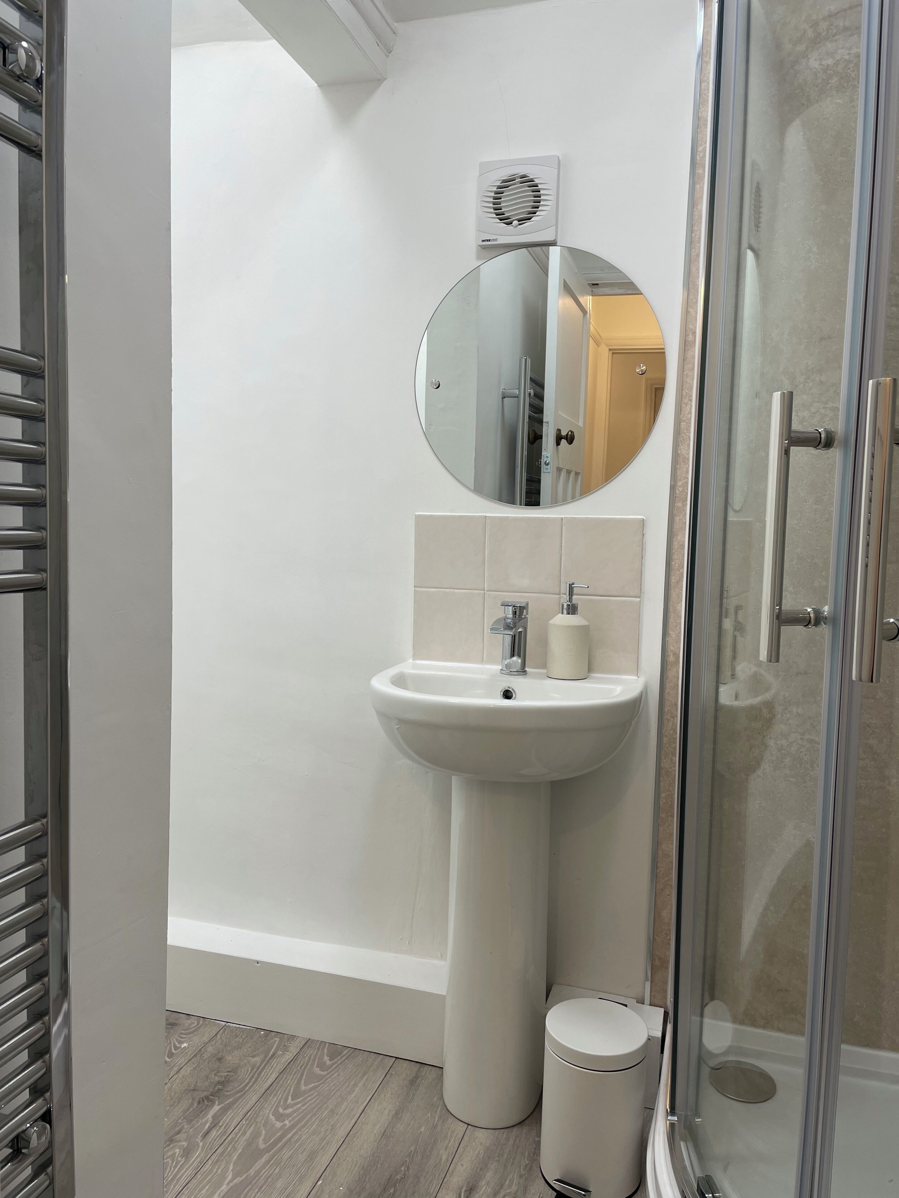 Et badeværelse med et håndvaskesæt, et spejl, en bruseniche og et toilet.