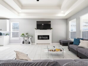 Ein modernes Wohnzimmer mit Kamin, Flachbildfernseher und einer Couch.