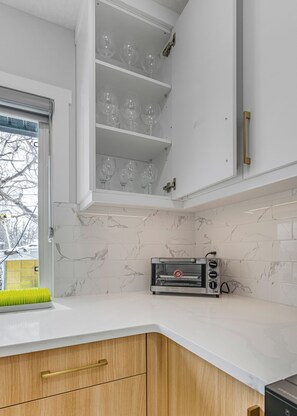 Eine Küche mit weißen Schränken, einem eingebauten Backofen und einem Fenster mit Blick auf Bäume.