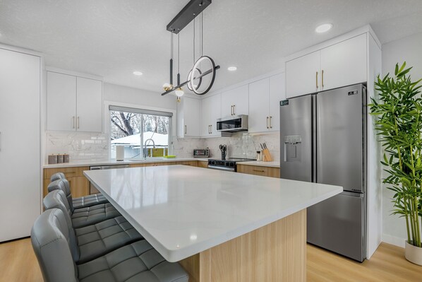 A modern kitchen with a large island, stainless steel appliances, and a seating area.