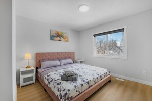 A bedroom with a bed, nightstands, a lamp, a window, and a painting on the wall.
