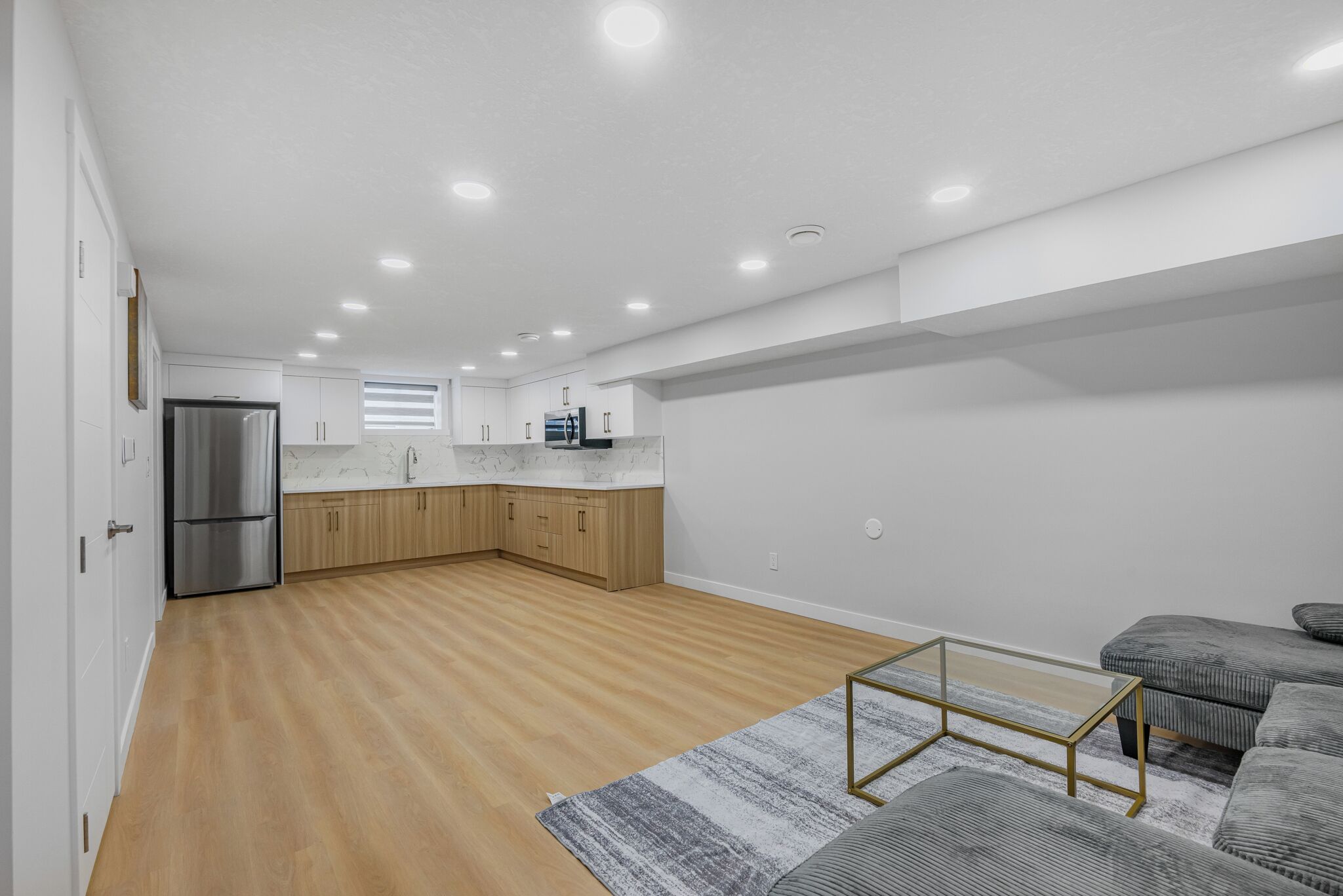 A modern kitchen with wooden cabinets, a stainless steel refrigerator, and a marble countertop.