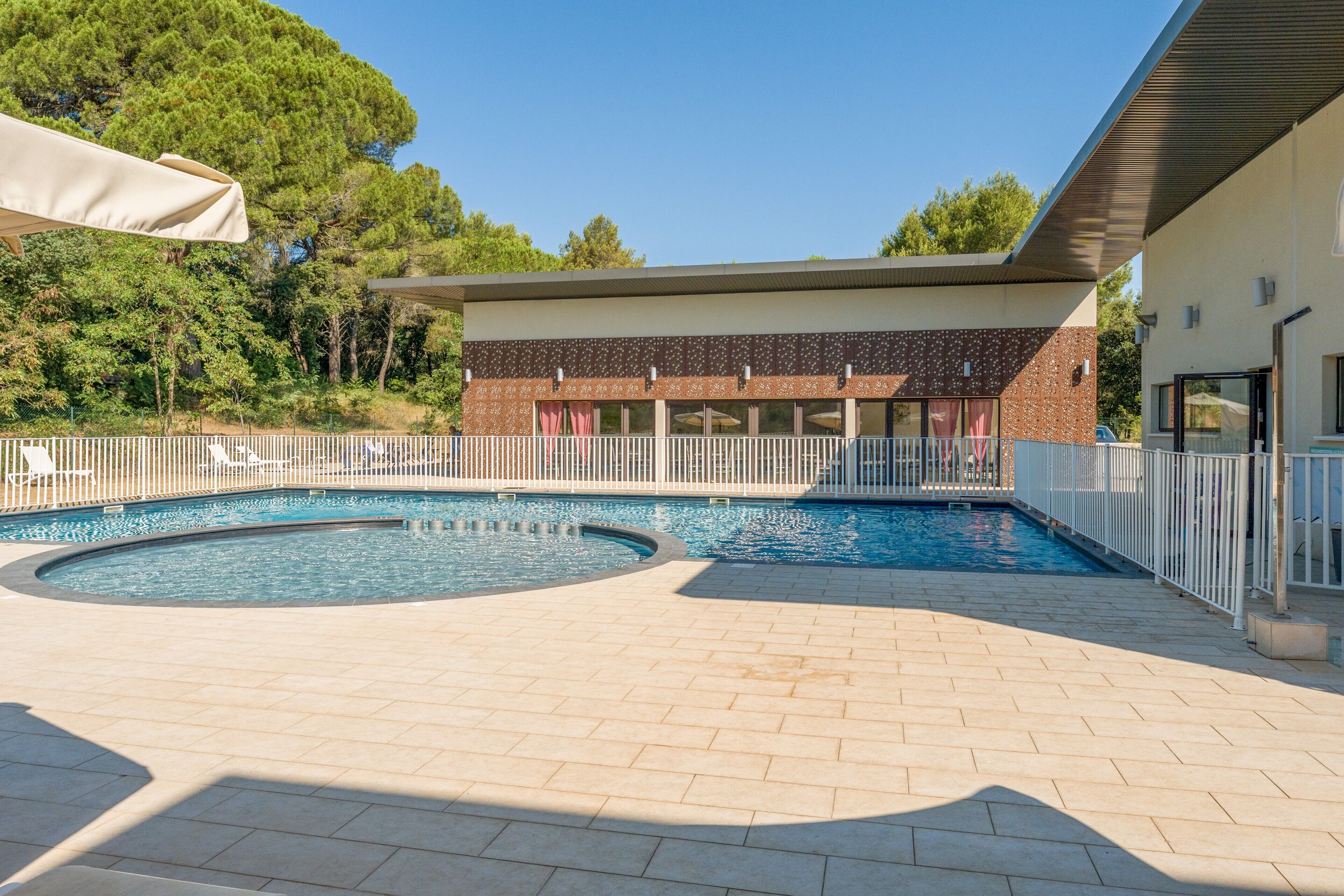 A swimming pool area with a brick building in the background.