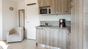 A modern kitchen with a microwave, coffee maker, and a chair.