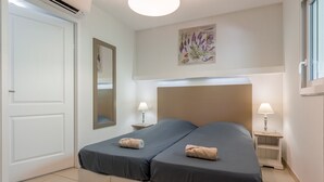 A double bed with two bedside tables, a mirror, and a wall-mounted plant.
