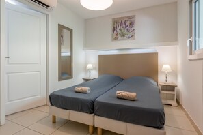 A double bed with two bedside tables, a mirror, and a wall-mounted plant.