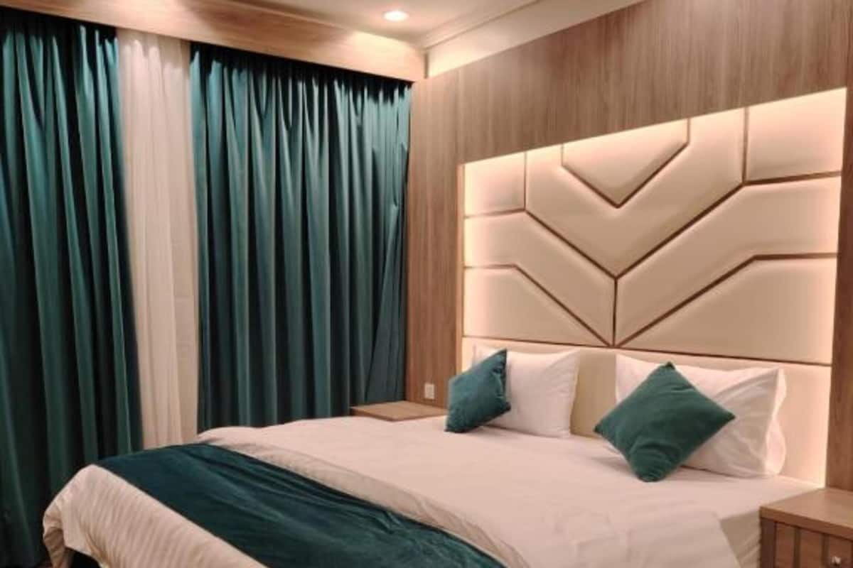 Un lit bien fait, avec une tĂȘte de lit, une table de chevet et un tapis Ă motifs.