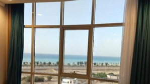 A bedroom with a large window, a bed, and a view of a landscape. - HMM Serviced apartments Umluj (umm lajj)