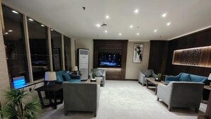 A modern living room with a flat-screen TV, multiple seating areas, and a large window. - HMM Serviced apartments Umluj (umm lajj)
