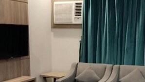 A living room with a sofa, a coffee table, a TV, and a window with curtains. - HMM Serviced apartments Umluj (umm lajj)