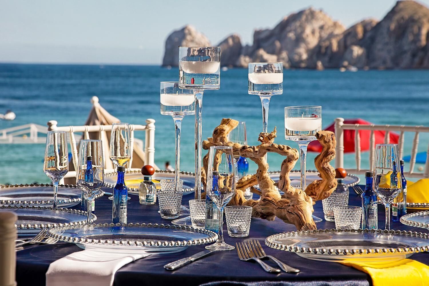 A table set for a meal with clear glasses, bottles, and a decorative centerpiece.