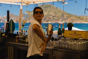 Un barman tenant un shaker à cocktails, avec des bouteilles de champagne Moët & Chandon et des verres sur le comptoir.