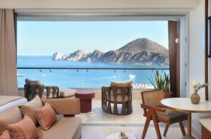 Un balcón con vista al mar y a las montañas, amueblado con un sofá, sillas y una mesa.