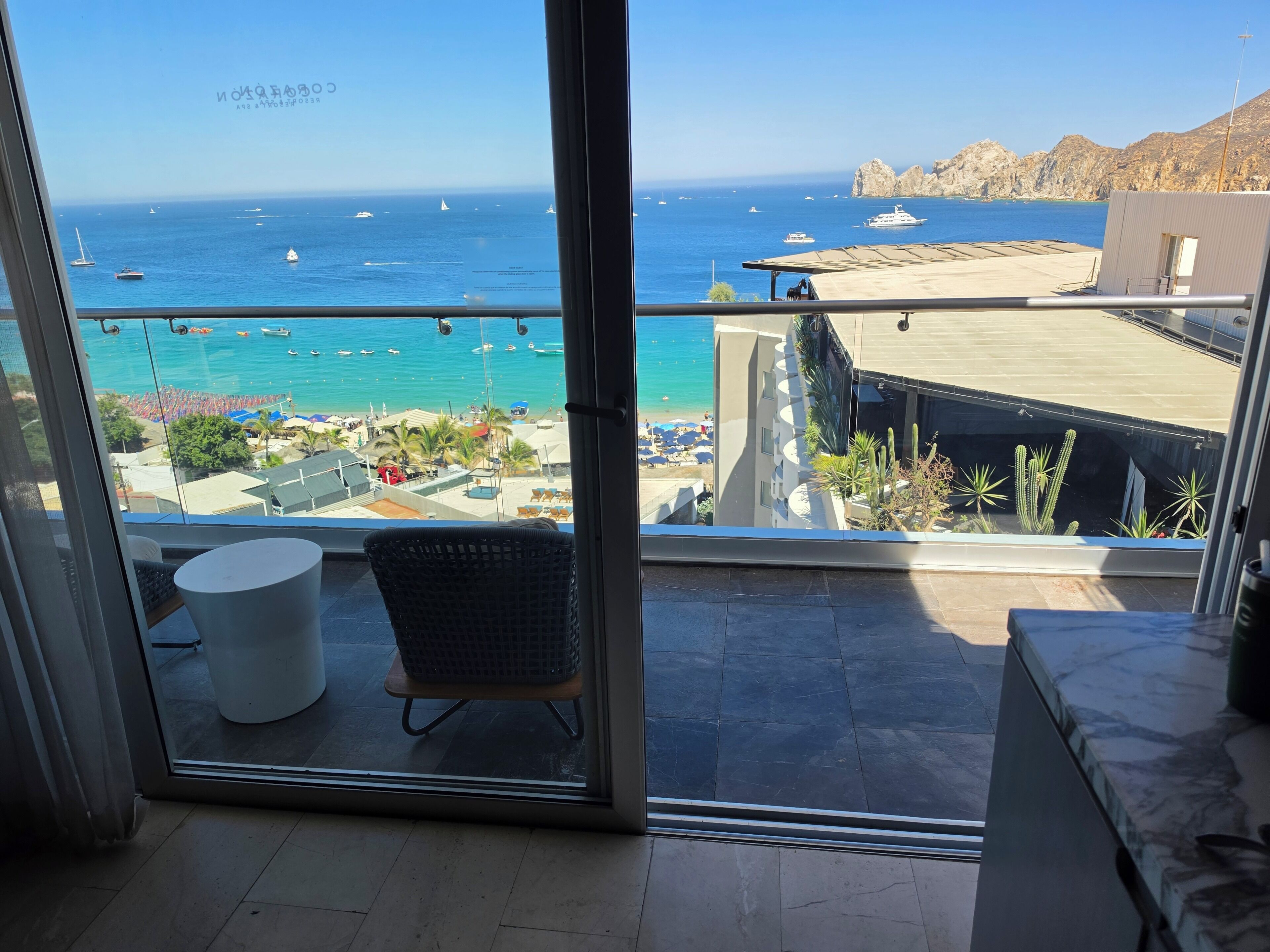 A balcony with a view of the sea, a chair, and a table.