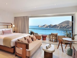 Un dormitorio con una cama grande, un sofá, una mesa de comedor y vistas al mar.