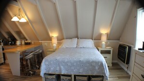 Ein Schlafzimmer mit einem Bett, zwei Nachttischen, einem Schreibtisch mit Stühlen und einem Fenster.