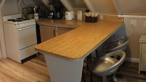 Eine Küche mit einer Holzausziehtafel, einem weißen Herd, einer Mikrowelle und einer Pendelleuchte.