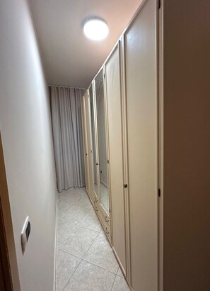 En smal gang med loftlampe, en skydedør og et gardin.