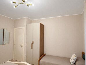 Une chambre à coucher comprenant un lit, une armoire, un miroir et un luminaire au plafond.