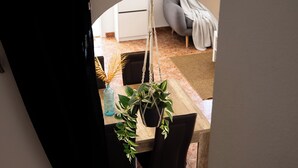 Ein Essbereich mit einem Holztisch, schwarzen Stühlen und hängenden Pflanzen.