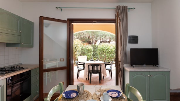 A compact kitchen with a dining area, a TV, and a view of the outdoors. - Casa del Leccio F4 by Wonderful Italy (San Teodoro)