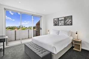 A bedroom with a large bed, a bench, a desk, and a nightstand. - Bright Apartment Near St Kilda Beachfront (Melbourne)